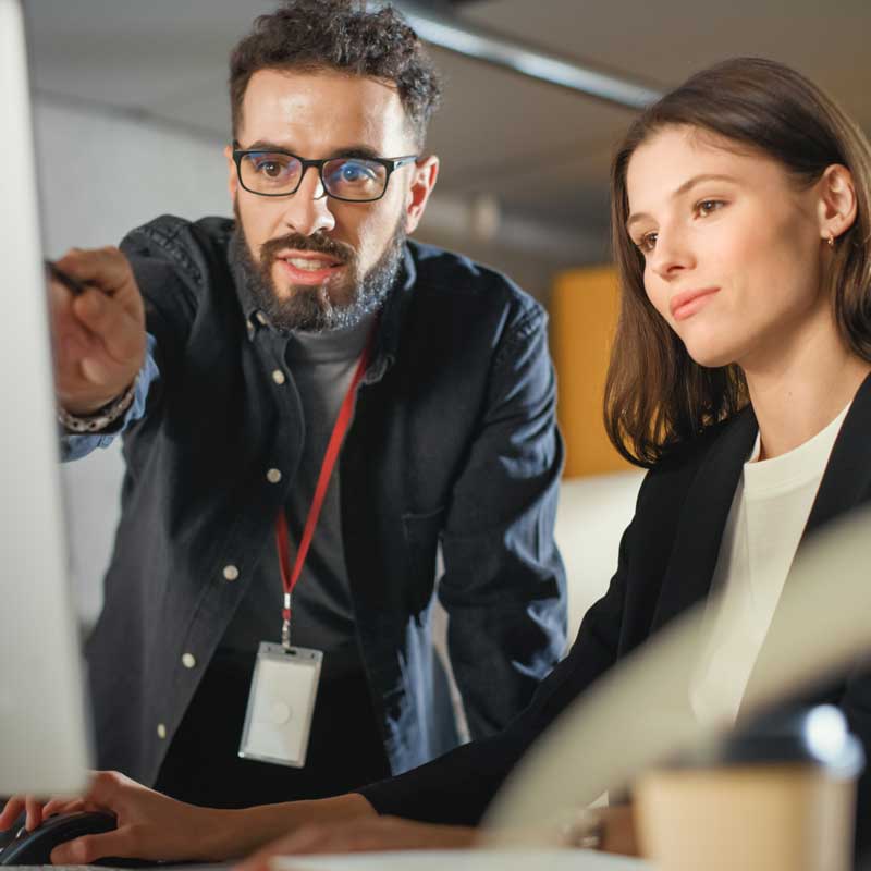 Man pointing at computer and woman looking while collaborating